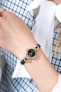 Vue détaillée d'une montre à quartz vintage en or rose avec bracelet en cuir vert au poignet