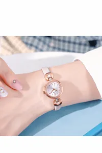 Montre à quartz élégante en or rose avec bracelet en cuir blanc porté au poignet