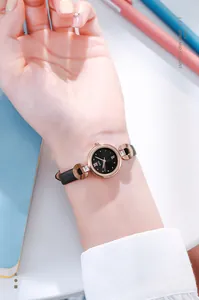 Détails d'une montre élégante pour femme en or rose avec cristaux et bracelet en cuir noir