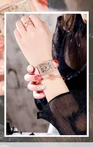 Close-up of elegant square diamond watch with pink leather strap and rose gold jewelry