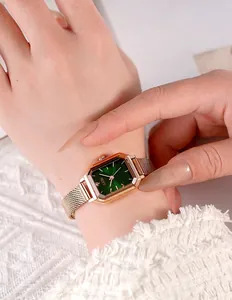 Detail of elegant rectangular rose gold watch with green dial on woman's wrist