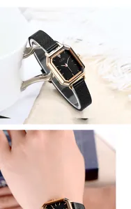Close-up of elegant gold rectangular watch with black mesh strap and minimalist dial