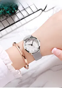 Close-up of women's quartz watch with embossed clover dial and grey leather strap