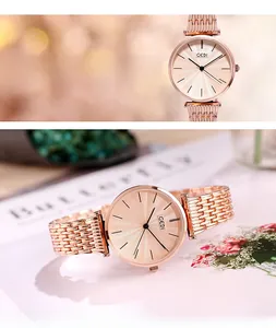 Macro detail of a women's rose gold watch face with sunburst texture and mesh strap