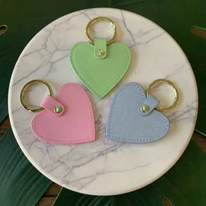 Heart shaped leather keychains in mint, pink and blue with gold rings on marble plate