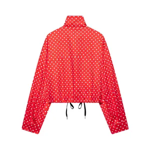 Detail of red polka dot high collar jacket with adjustable drawstring hem and silky finish