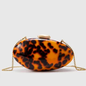 Detail of tortoise shell pattern acrylic clutch with gold pebble clasp and chain strap