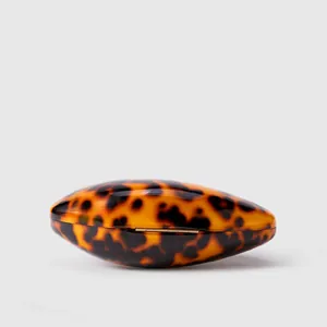 Macro detail of acrylic evening bag featuring a brown tortoiseshell texture and metal hinge