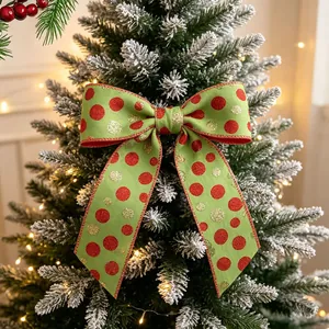 Detail of green polka dot Christmas bow with red glitter on a snowy pine branch