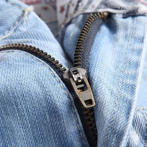 Detailed close-up of vintage copper zipper on light blue denim shorts with sturdy stitching