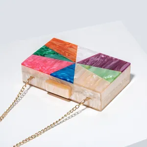 Macro detail of geometric acrylic clutch showing colorful marble texture and gold chain