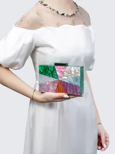 Macro detail of multicolored acrylic clutch showing marble texture and emerald clasp