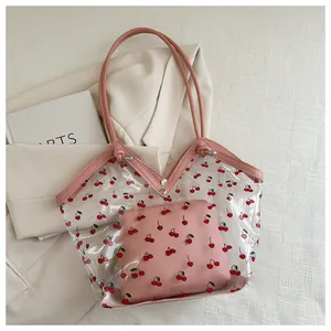 Detail of transparent PVC tote bag with cherry prints and pink leather handles