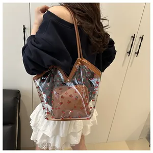 Detail of transparent PVC cherry print tote bag featuring a brown inner pouch and faux leather straps
