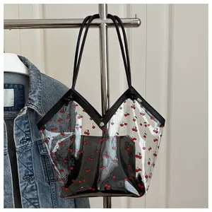 Macro view of transparent PVC tote bag with red cherry prints and black inner pouch