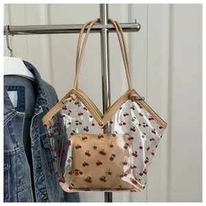 Detail of transparent PVC tote bag with red cherry print and leather trim accents