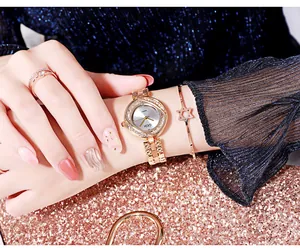Gros plan d'une montre à quartz or rose pour femme avec lunette en strass et parure assortie