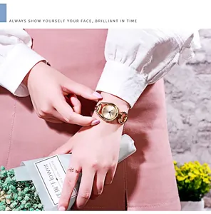 Close-up of golden GEDI quartz watch with horseshoe buckle band and leaf ring on wrist