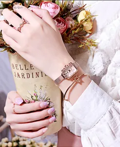 Primo piano dell'orologio quadrato in oro rosa con bracciale a stella e anelli da donna