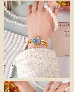 Close-up of golden luxury watch with rhinestone bezel and deep blue dial on model