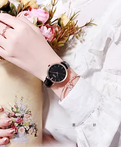Close-up of elegant black leather watch with rose gold heart bracelet on a female wrist