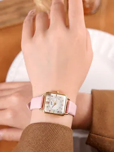 Primer plano de un reloj vintage cuadrado dorado con correa de cuero rosa en la muñeca
