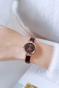Detail of elegant ladies watch with brown leather strap, rose gold case, and date window