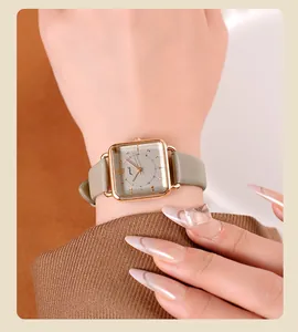 Primer plano de un reloj de cuarzo vintage con caja de oro rosa y correa de cuero verde en la muñeca