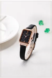 Detail of rose gold rectangular watch with black starry dial and leather strap