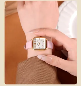 Primer plano del reloj gedi cuadrado dorado con correa de cuero rosa en la muñeca
