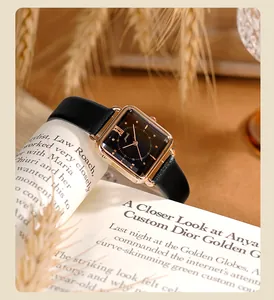 Reloj vintage cuadrado para mujer con correa de cuero negro sobre un libro elegante