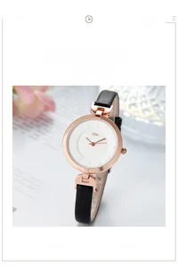 Detail of rose gold watch case with white dial and black leather strap on lifestyle background