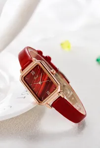 Detailed close-up of a rectangular rose gold quartz watch with a red textured dial