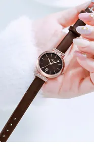 Detail of rose gold quartz watch with diamond accents and brown leather strap on wrist
