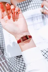 Close-up of women's vintage rectangular watch with malachite texture and red leather strap