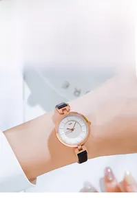 Close-up of elegant rose gold watch with white textured dial and black leather strap