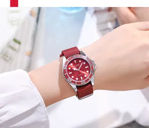 Détail d'une montre à bracelet NATO rouge avec lunette crantée argentée au poignet
