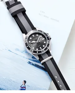 Gros plan d'une montre GEDI avec cadran brossé et bracelet NATO gris sur un livre