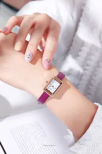Montre rectangulaire élégante or rose avec bracelet en cuir bordeaux au poignet