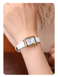 Close-up of a vintage square quartz watch with a white leather strap and roman numerals