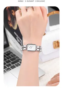 Detail of silver rectangular watch with braided chain strap on wrist with fashion accessories