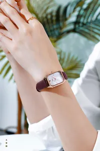 Close-up of GEDI square rose gold quartz watch with a burgundy leather strap on wrist