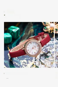Vue détaillée de la montre en or rose avec diamants sur fond malachite et bracelet rouge