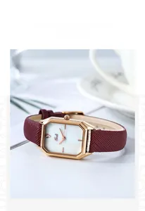 Close-up of a square gold watch with mother of pearl dial and red leather strap