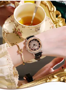 Gros plan sur montre en or rose avec strass, bracelet en cuir noir et bracelet étoile