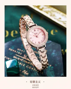 Detail of rose gold quartz watch with rhinestone bezel and pink dial on dark background