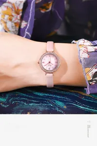 Gros plan d'une montre en or rose avec strass et bracelet en cuir rose sur un poignet