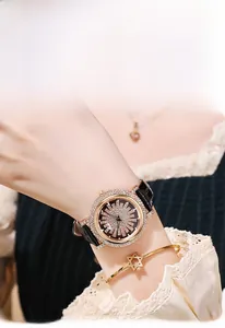 Photo lifestyle d'une montre de luxe dorée avec strass et bracelet en cuir noir