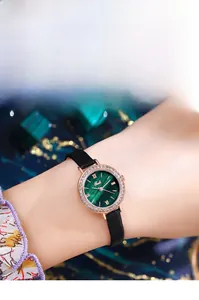 Gros plan de montre en or rose avec cadran vert et cristaux sur un poignet féminin
