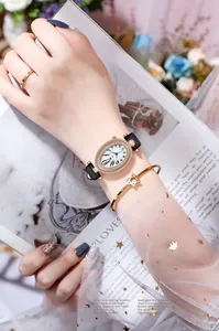 Vue macro de la montre ovale en or rose avec lunette en cristal et bracelet cuir noir